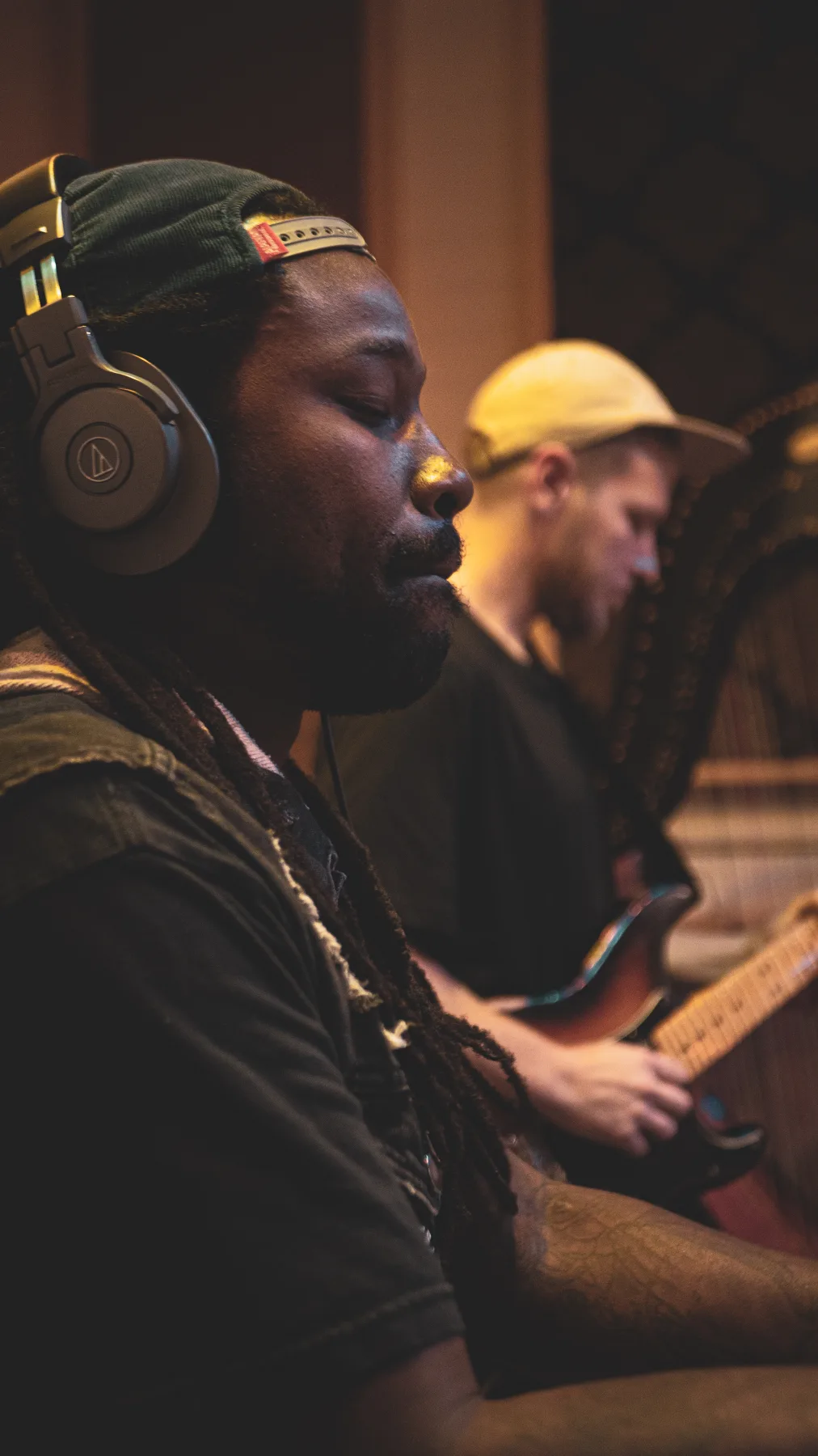 Close view of two musicians wearing headphones during a recording session.